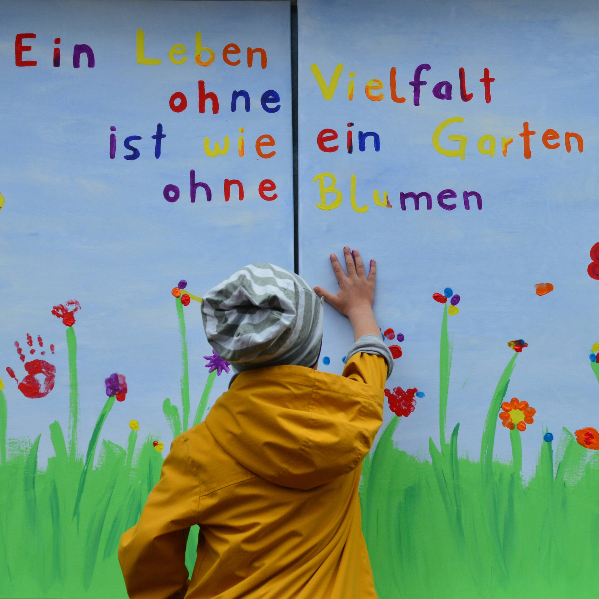 Ein Kind drückt seine Hand auf ein großes Fensterplakat