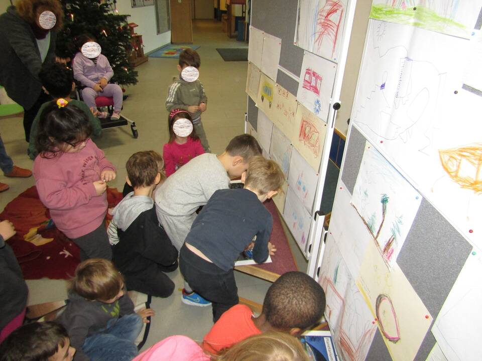 Mehrere Kinder schauen 2 Jungs zu die ihre Wünsche anheften.