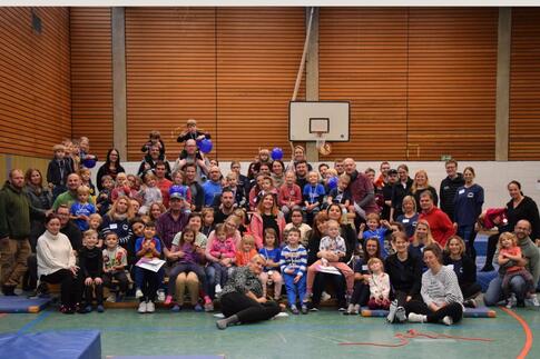 Viele Menschen mit vielen Kindern in einer Sporthalle auf einem Gruppenfoto.