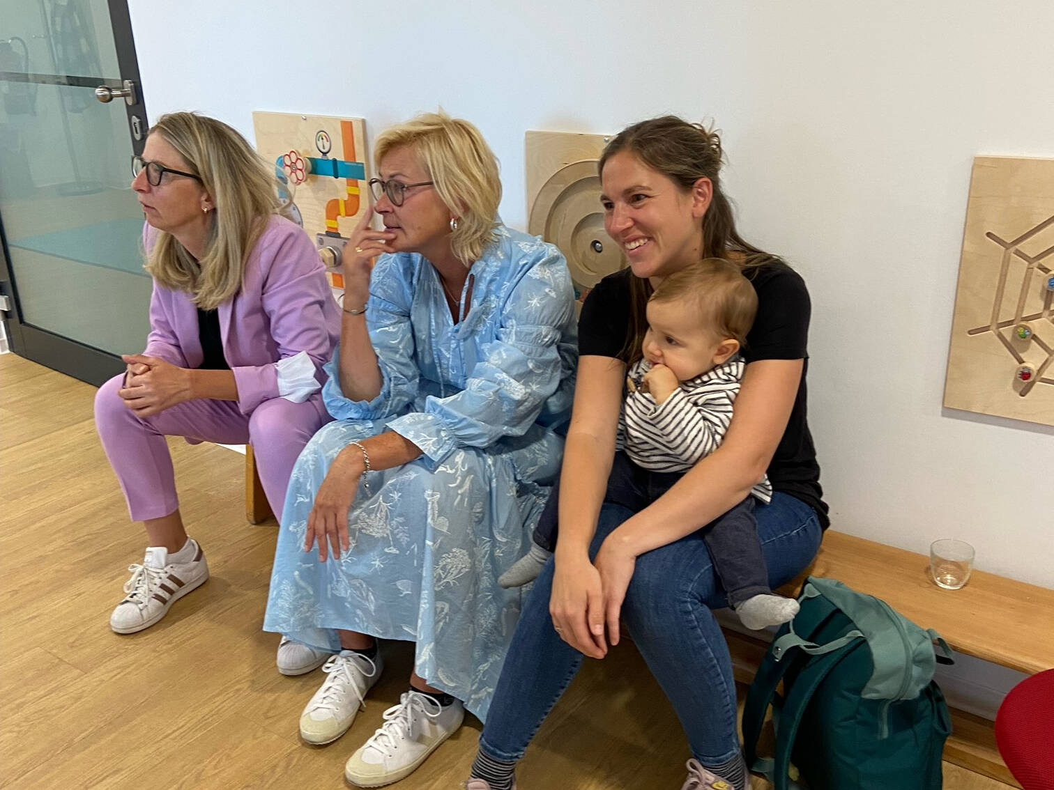 Drei Frauen sitzen auf einer Holzbank.