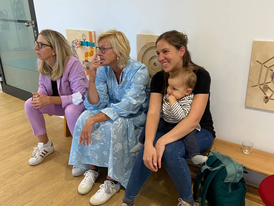 Drei Frauen sitzen auf einer Holzbank.