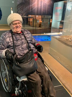 Eine Frau mit einer schwarzen Tasche im Rollstuhl.