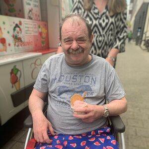 Ein Herr im Rollstuhl mit einem Becher Eis.