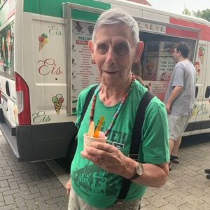 Ein Herr im grünen T-Shirt mit einem Eis in der Hand.