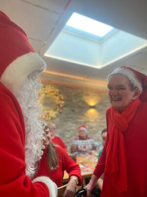 Eine Person mit Nikolausmütze lächelt den Nikolaus an.