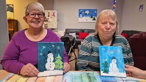 Zwei Frauen mit ihren Bildern, darauf zu sehen sind Schneemänner.