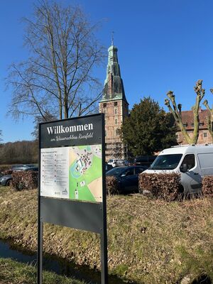 Das Schloss und im Vordergrund ein Willkommensschild