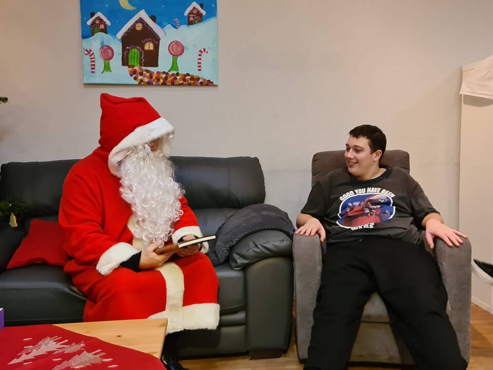 Ein Herr sitzt neben dem Nikolaus im Sessel.