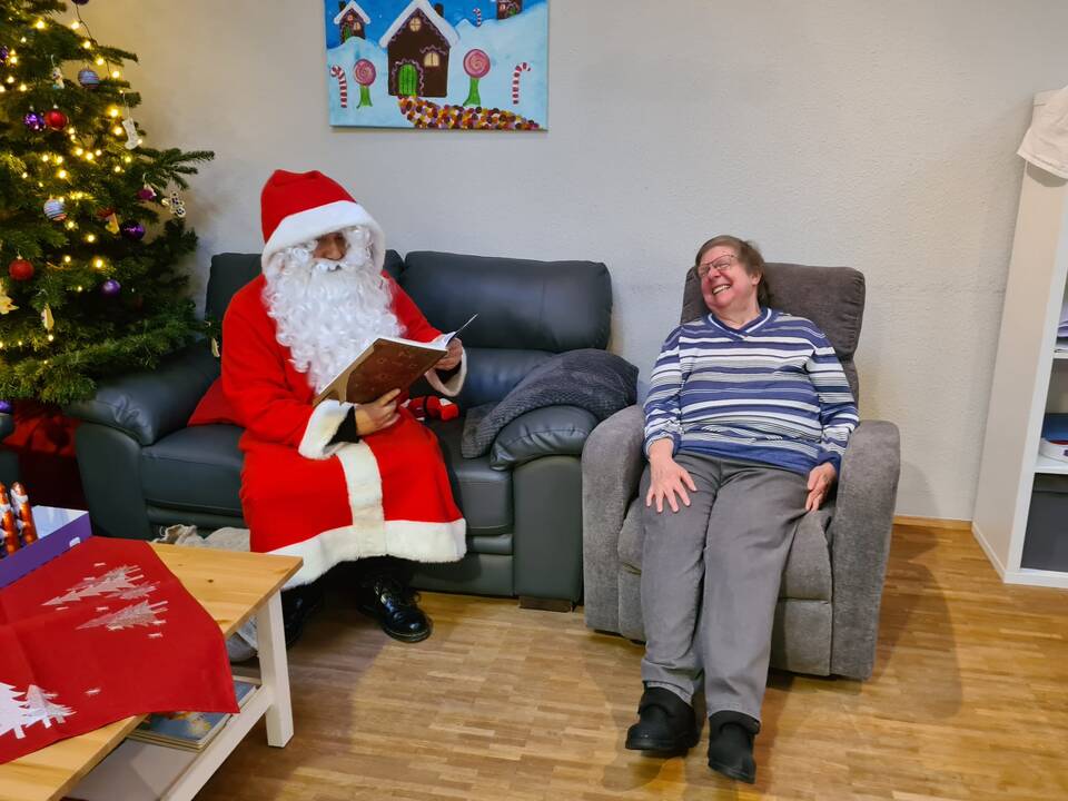 Eine Dame sitzt neben dem Nikolaus im Sessel.