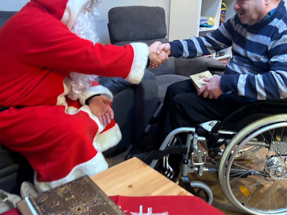 Ein Mann im Rollstuhl und der Nikolaus geben sich die Hand.