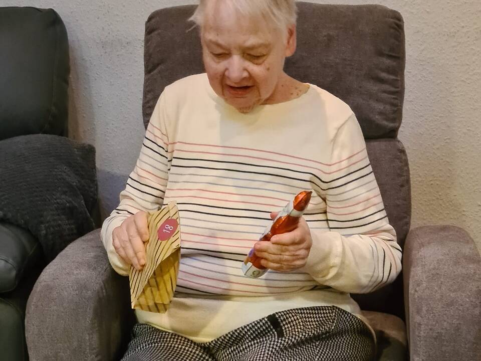 Eine Frau hält ein Geschenk und einen Schokoladennikolaus in den Händen.