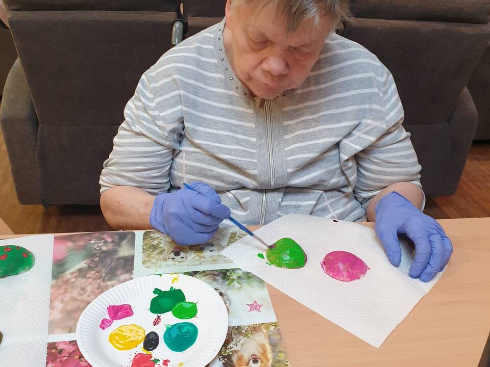 Eine Frau sitzt am Tisch und malt.