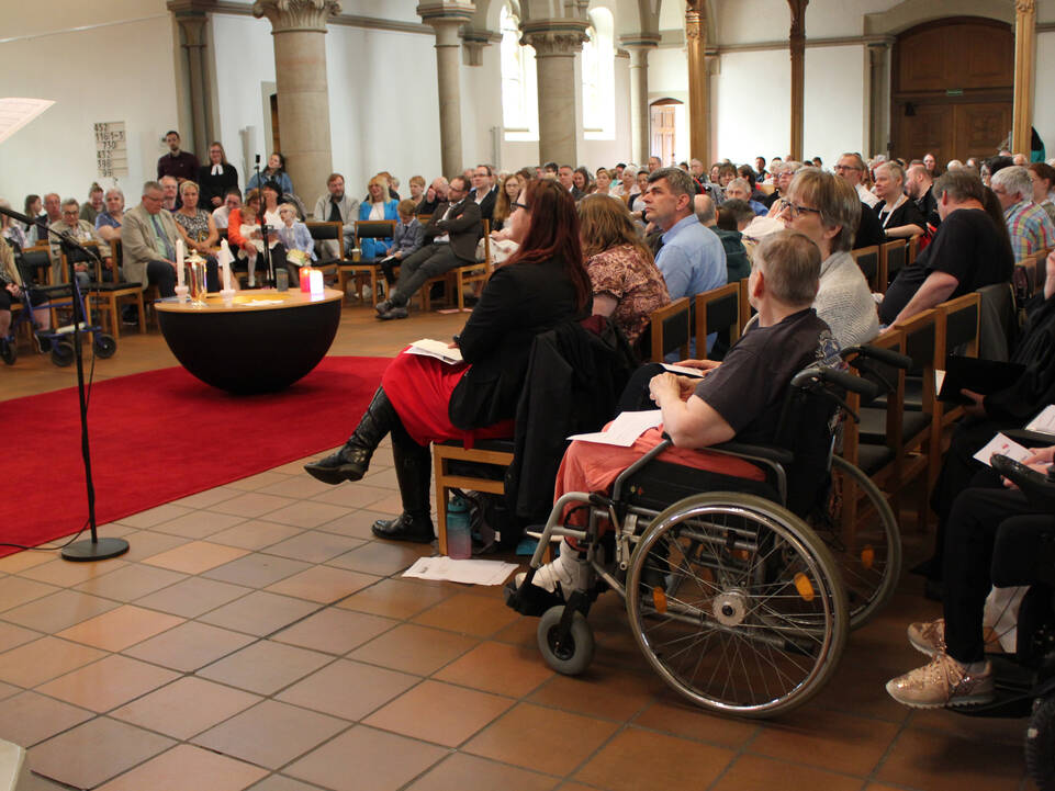 Kerzen stehen in der Mitte der Kirche und viele Menschen sind anwesend.