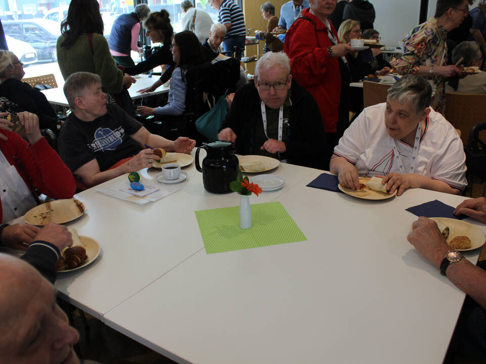 Menschen sitzen zusammen an Tischen und essen  etwas.