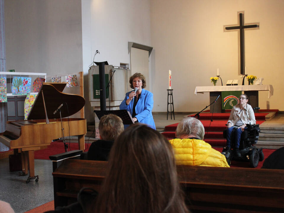 Eine Frau im blauen Blasser hält ein Mikrofon in der Hand.