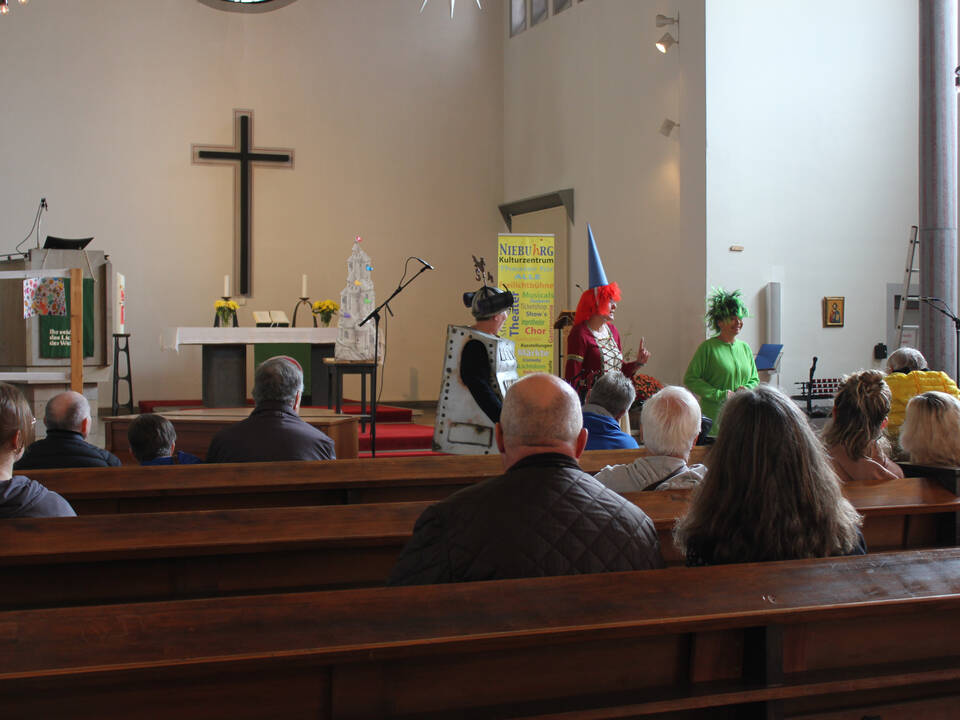 Einiige Personen sitzen in den Bänken einer Kirche.