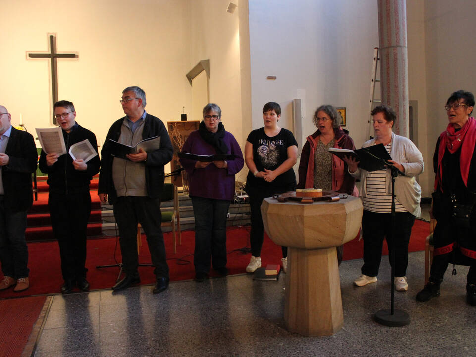 Drei Männer und vier Frauen sstehen in der Kirche und singen.
