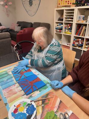 Eine Frau drückt ihre Hand, mit Farbe auf ein Bild.