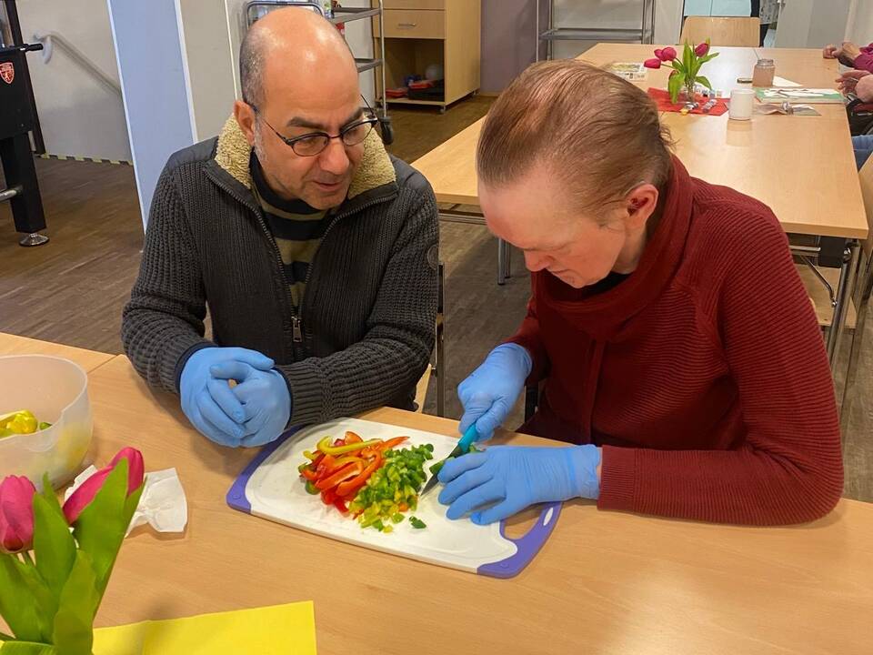 Ein Mann schneidet Gemüse an einem Tisch.