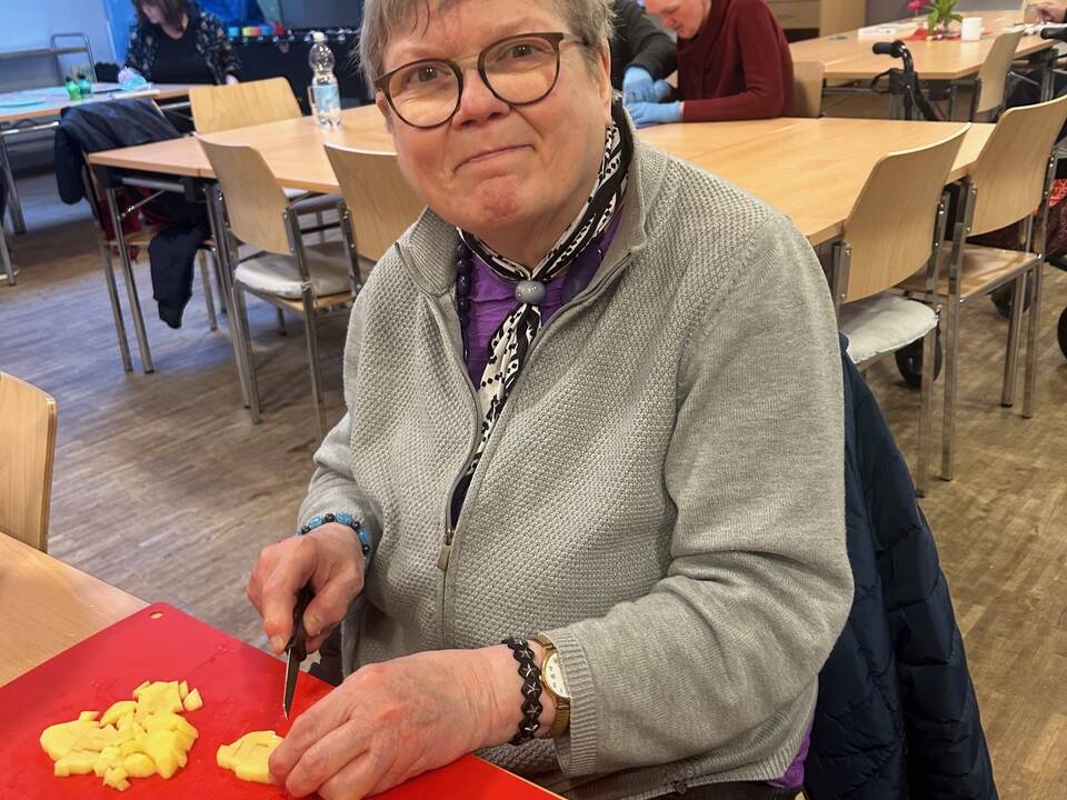 Eine Frau schneidet Kartoffel in Stücke.