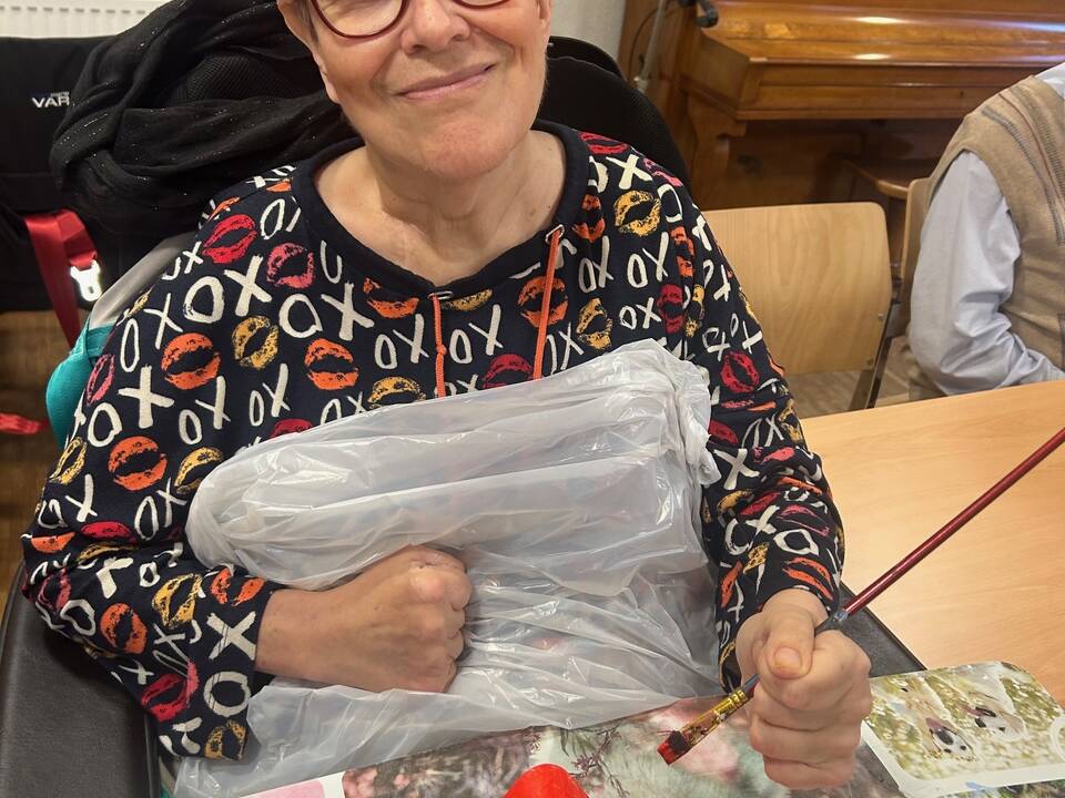 Eine Frau im Rollstuhl bemalt eine Maske.