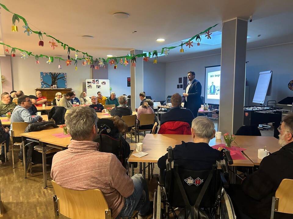 Ein Mann steht vor den Gästen und redet.