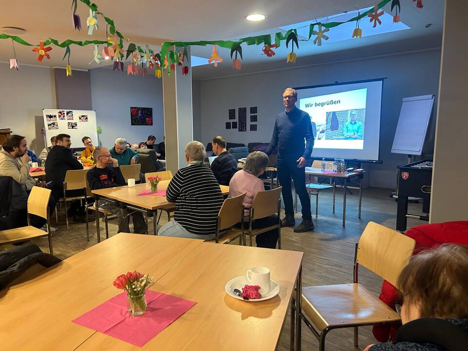 Ein Mann steht vor den Gästen.