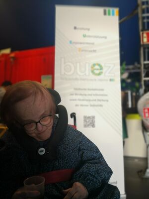 Eine Person im Rollstuhl vor einem Rollup.