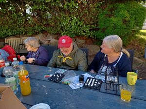 Bewohner sitzen draussen am Tisch und spielen.