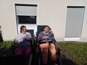 Zwei Personen sitzen draussen in der Sonne.