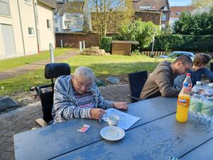 Eine Bewohnerin im Rollstuhl sitzt draussen am Tisch.