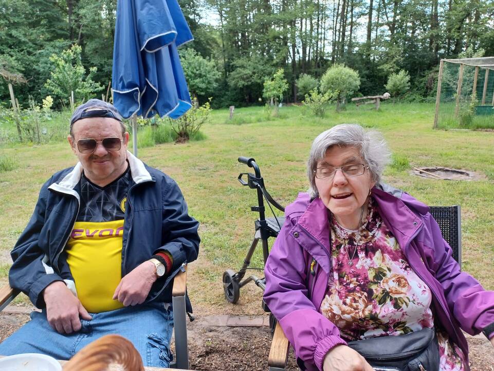 Ein Mann und eine Frau sitzen draußen an einem Tisch.