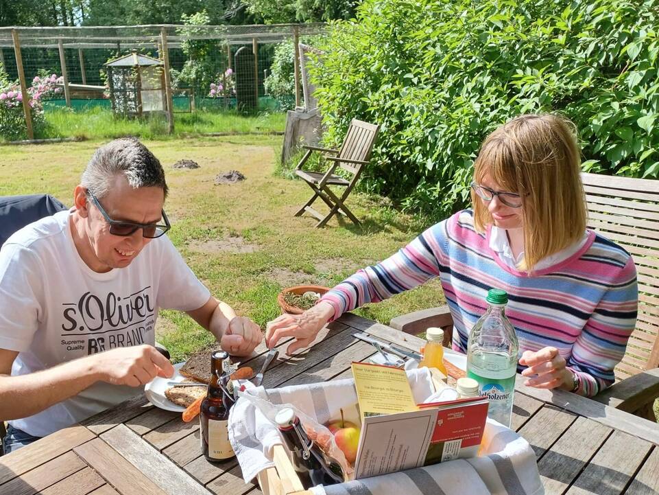 Ein Mann und eine Frau schmieren sich jeweils ein Brot.