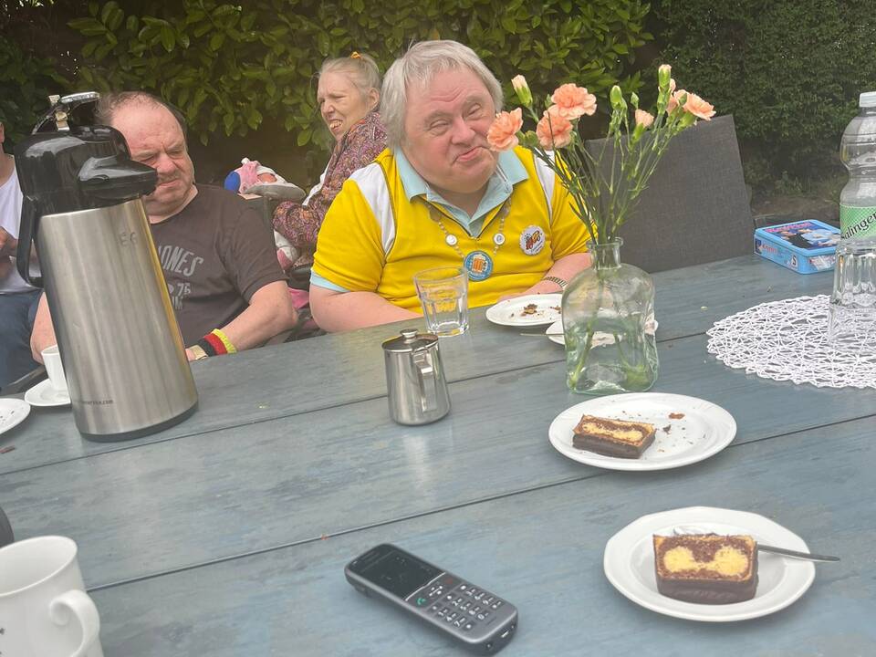 Eine Person sitzt am Tisch, Kuchen liegt auf Tellern.