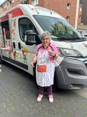 Eine Frau steht am Eiswagen und hält ein Eis in der Hand.