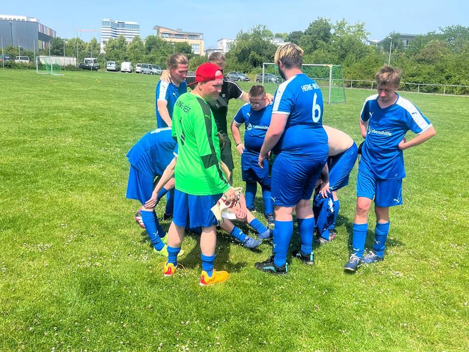 Ein Spieler liegt auf dem Boden, andere stehen drumherum.