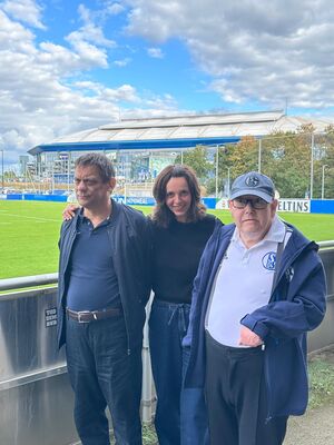 Zwei Schalkefans mit Begleitung am Spielfeldrand.
