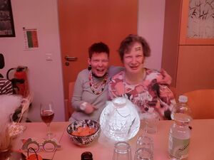 Zwei Personen sitzen am Tisch und nehmen sich in den Arm.