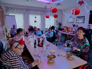 Einige Bewohner sitzen am Tisch in einem Raum.