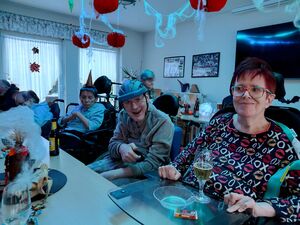 Personen mit Hilfsmitteln ssitzen am Tisch und haben Getränke.