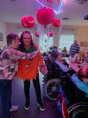 Eine Frau umarmt eine Frau mit Kürbiskostüm.