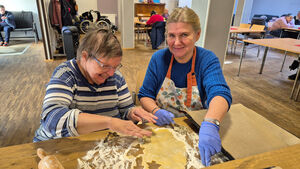 Zweii Frauen legen Plätzchenteig aufs Blech.