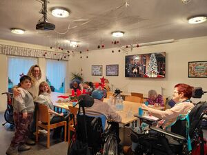 Viele Menschen sitzen mit und ohne Hilfsmittel in einem Raum .an eiinem großen Tisch.