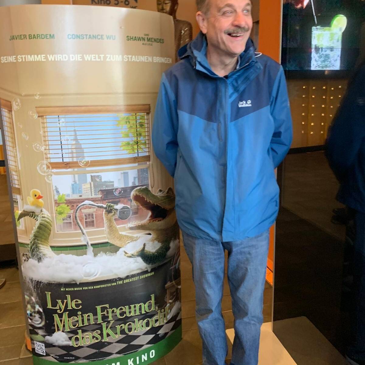 Ein Mann neben einem Aufsteller mit Werbung für den Film.