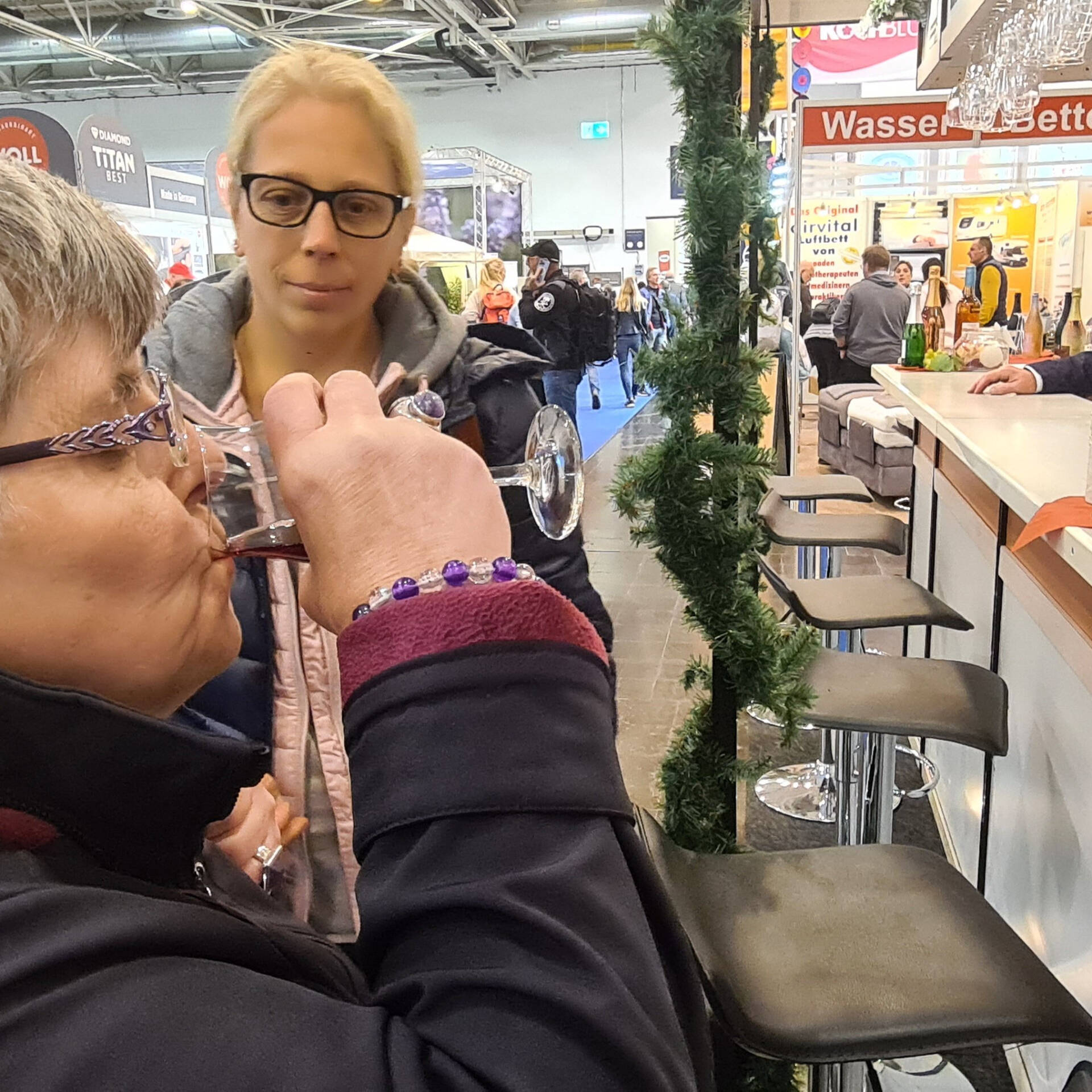 Eine Frau trinkt etwas, eine andere schaut ihr dabei zu.