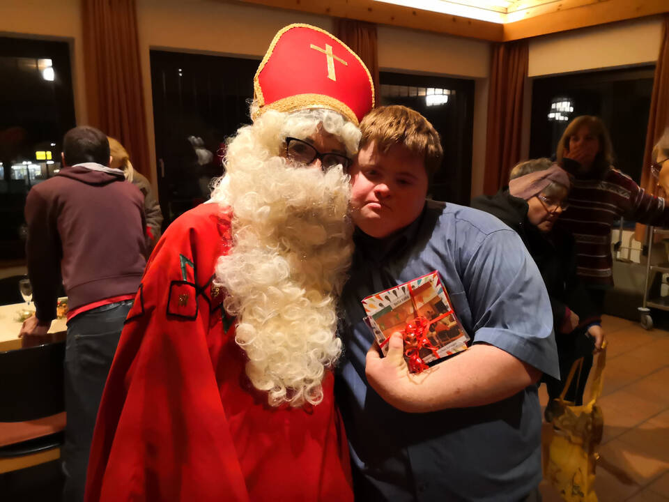 Ein junger Mann und der Nikolaus Arm in Arm.