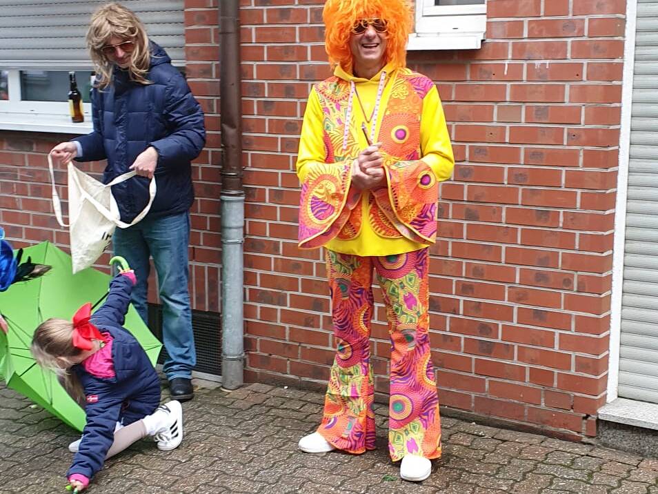 Ein Clown vor einem Haus auf dem Bürgersteig.