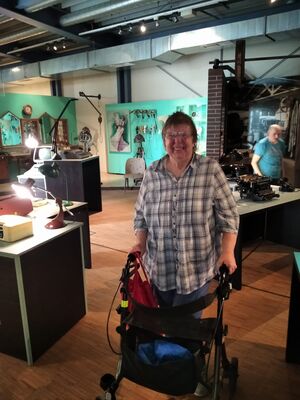 Eine Person mit Rollator steht in einem Ausstellungsraum.