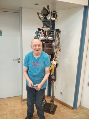 Ein Mann steht vor einer Skulptur.