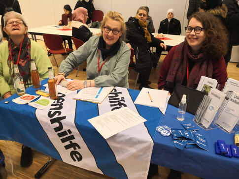 Drei Frauen mit und ohen Hilfsmittel sitzen an einem Tisch.